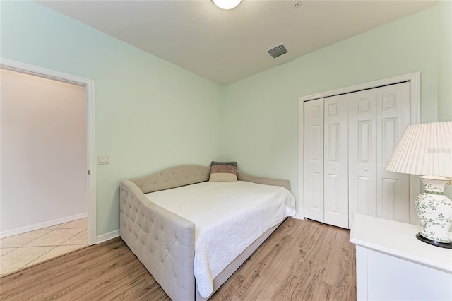 bedroom with light hardwood / wood-style floors and a closet