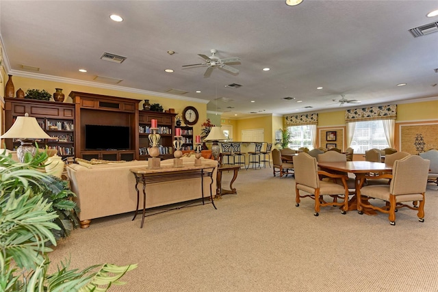 carpeted dining room with crown molding and ceiling fan