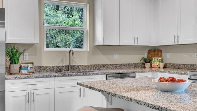 kitchen with light stone counters, sink, and white cabinets