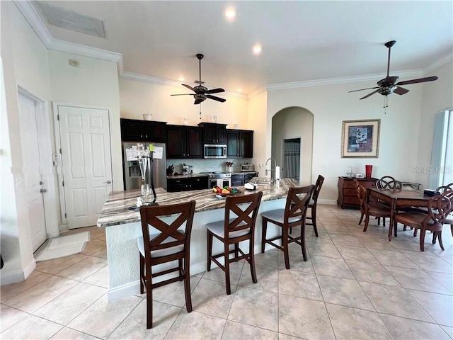 kitchen featuring light stone countertops, a spacious island, appliances with stainless steel finishes, sink, and light tile patterned flooring