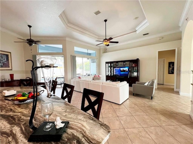 dining area featuring a raised ceiling, light tile patterned flooring, and crown molding