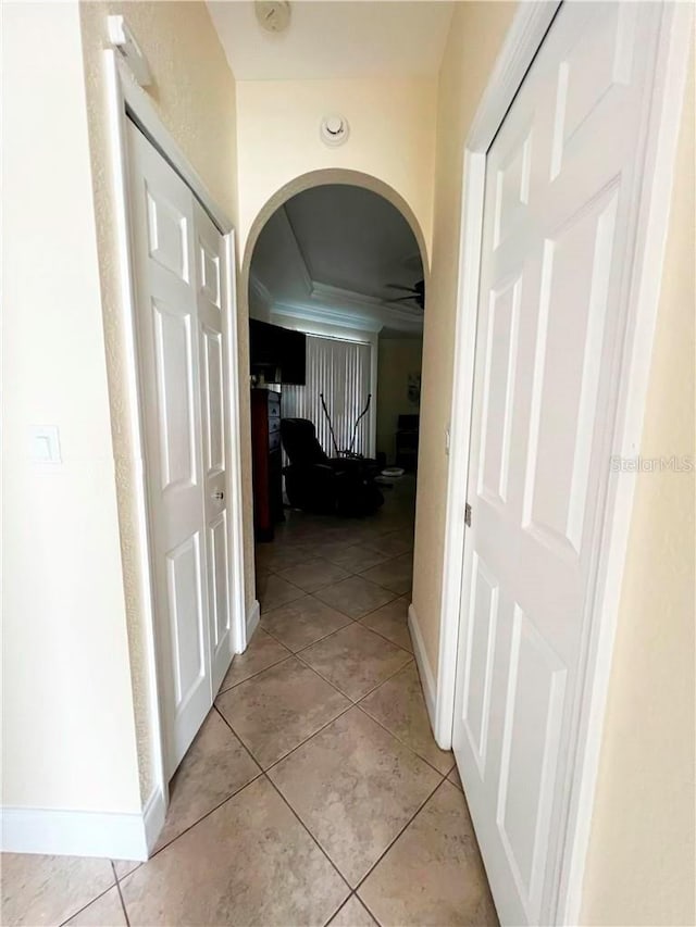 corridor with light tile patterned floors and crown molding