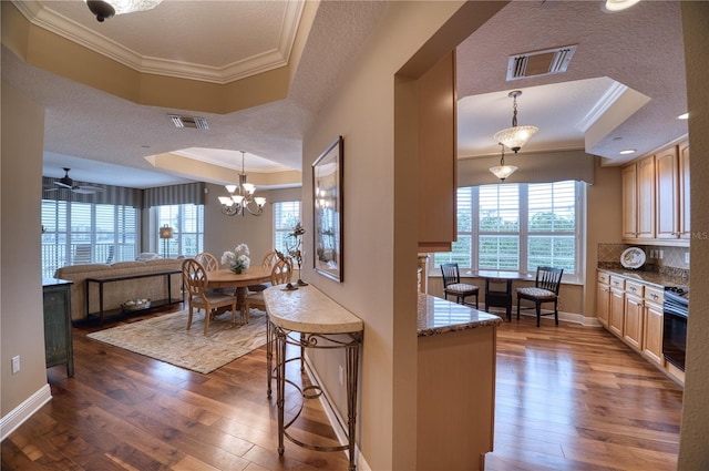 kitchen featuring crown molding, pendant lighting, dark wood-type flooring, and a tray ceiling