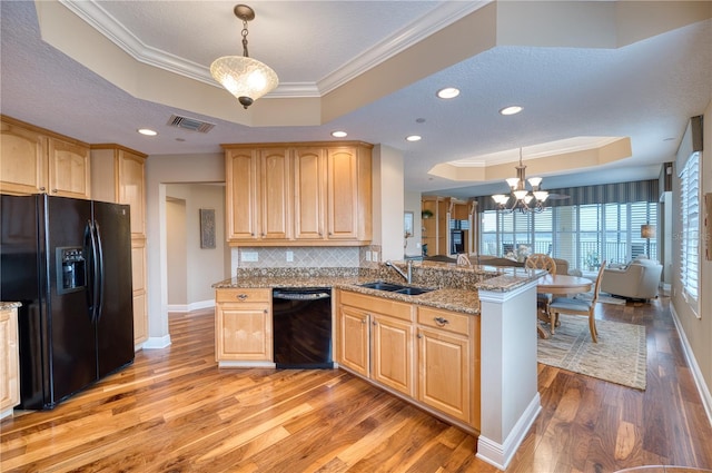 kitchen with black appliances, a raised ceiling, kitchen peninsula, and hanging light fixtures