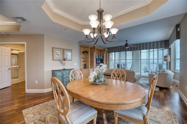 dining area featuring crown molding, dark hardwood / wood-style floors, a raised ceiling, and a textured ceiling