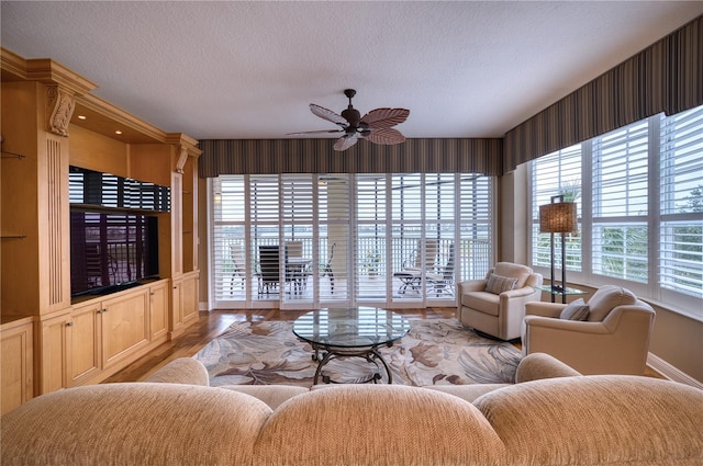 living room with wood-type flooring, a textured ceiling, and ceiling fan