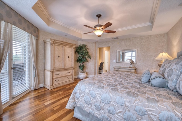 bedroom featuring ceiling fan, a raised ceiling, crown molding, and light hardwood / wood-style floors