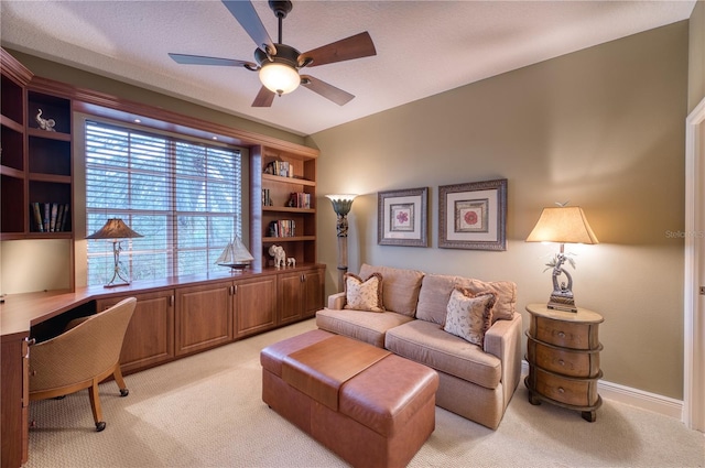 office area featuring ceiling fan, built in desk, and light carpet