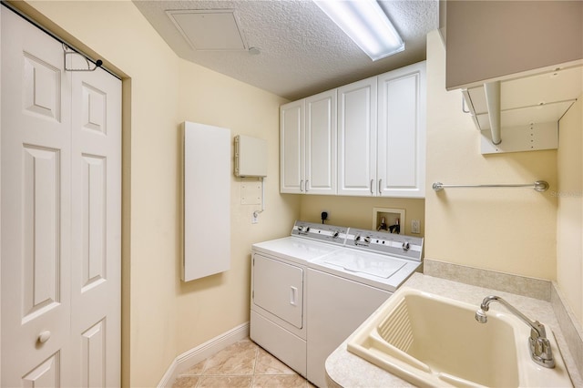 washroom with sink, washer and dryer, light tile patterned floors, cabinets, and a textured ceiling