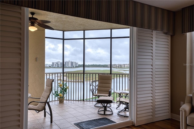 sunroom / solarium with ceiling fan and a water view