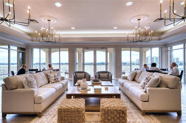 living room featuring plenty of natural light, a chandelier, a raised ceiling, and a water view