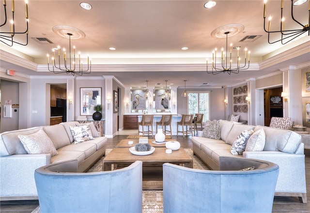 living room with hardwood / wood-style floors, a tray ceiling, crown molding, and a notable chandelier