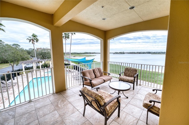 view of patio featuring a balcony, a fenced in pool, a water view, and an outdoor hangout area