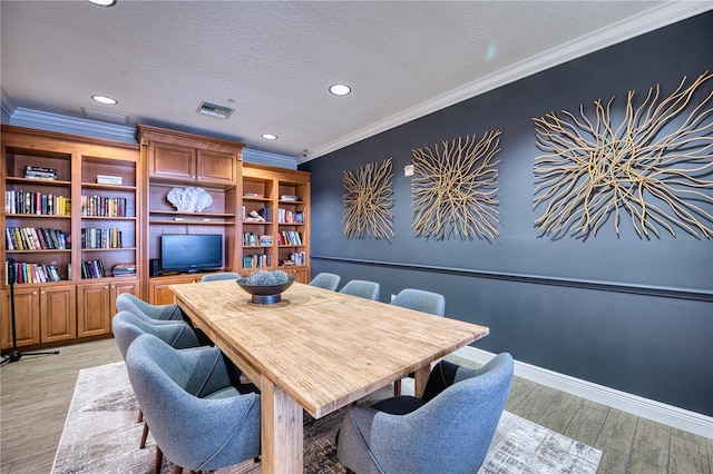 dining area featuring light hardwood / wood-style floors, a textured ceiling, and ornamental molding