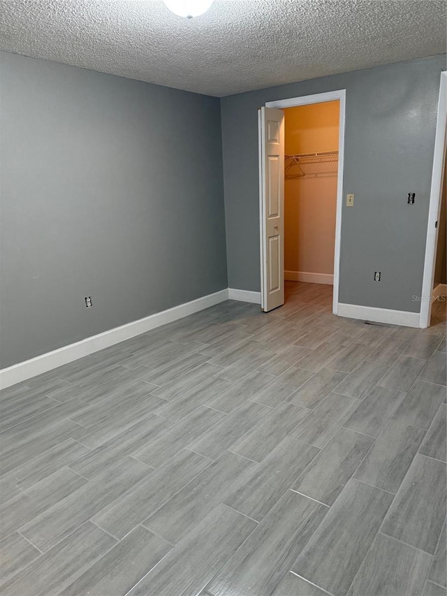 unfurnished bedroom featuring a walk in closet, a textured ceiling, and a closet