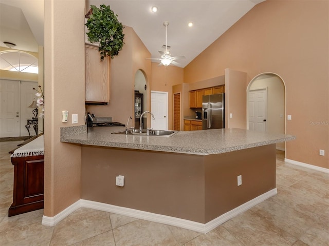 kitchen with kitchen peninsula, ceiling fan, sink, stainless steel fridge with ice dispenser, and high vaulted ceiling