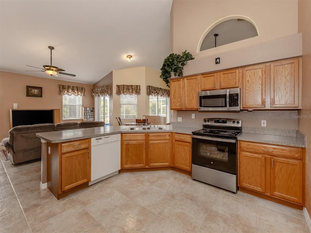 kitchen with kitchen peninsula, ceiling fan, sink, lofted ceiling, and stainless steel appliances