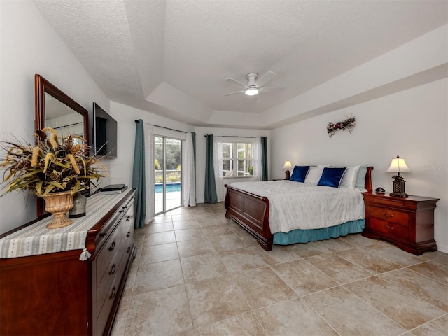 bedroom featuring ceiling fan, access to exterior, a textured ceiling, and a raised ceiling