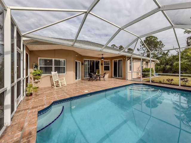 view of pool with ceiling fan, glass enclosure, and a patio area