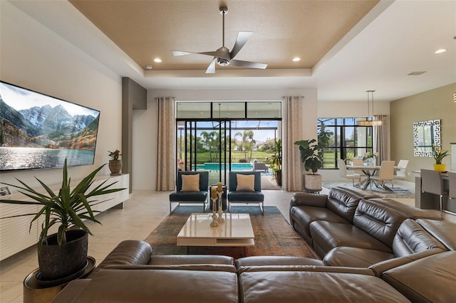 living room with ceiling fan and a raised ceiling