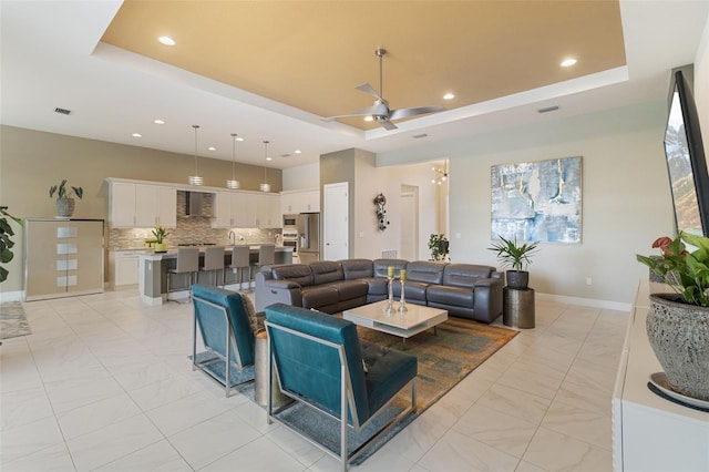 living room featuring a raised ceiling and ceiling fan