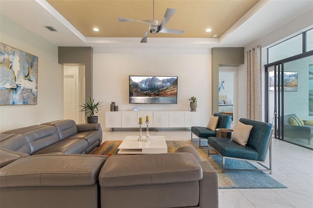 living room featuring ceiling fan and a raised ceiling