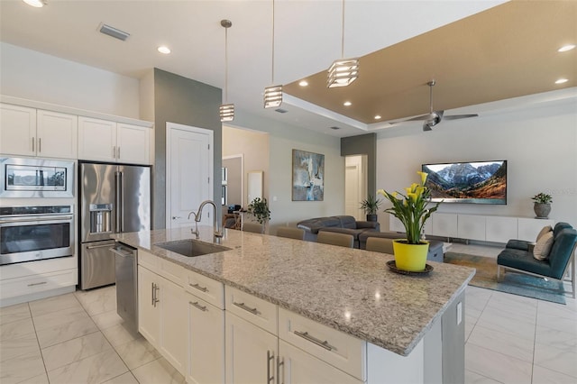 kitchen with sink, white cabinetry, pendant lighting, stainless steel appliances, and a kitchen island with sink