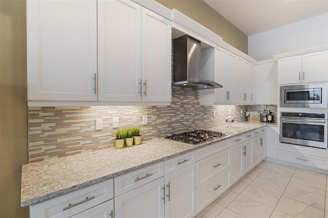 kitchen featuring appliances with stainless steel finishes, wall chimney range hood, white cabinets, and backsplash