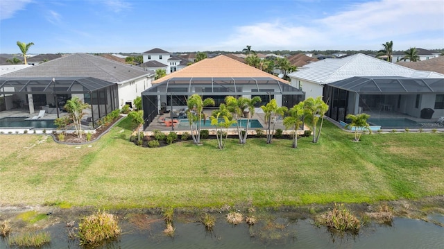 back of property with a water view, glass enclosure, and a lawn