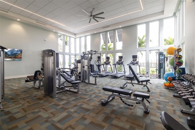 workout area with ceiling fan, a healthy amount of sunlight, and dark colored carpet