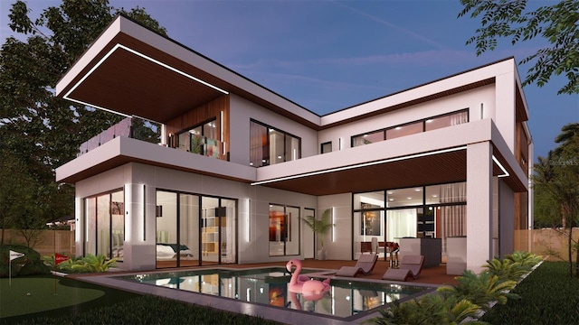 back house at dusk featuring a fenced in pool, a patio area, and a balcony