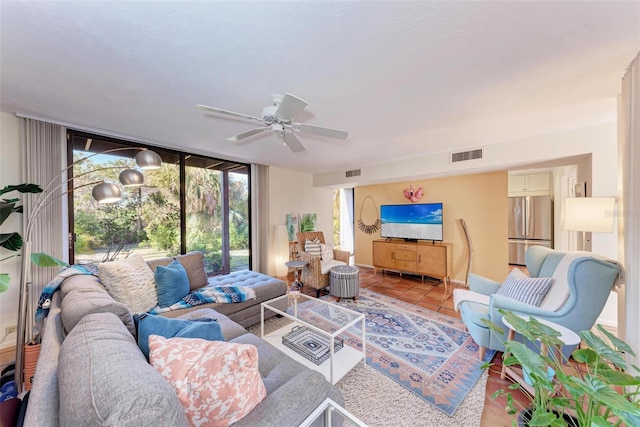 tiled living room featuring a wall of windows, visible vents, baseboards, and a ceiling fan