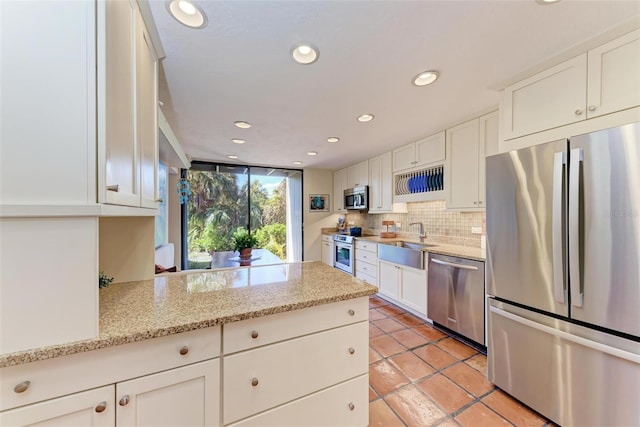 kitchen with stainless steel appliances, sink, white cabinets, and light stone counters