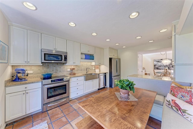 kitchen with light tile patterned flooring, sink, appliances with stainless steel finishes, white cabinets, and backsplash