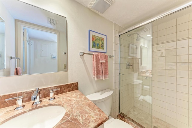 bathroom with walk in shower, vanity, and toilet