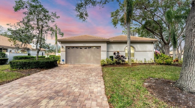 mediterranean / spanish home with a lawn and a garage