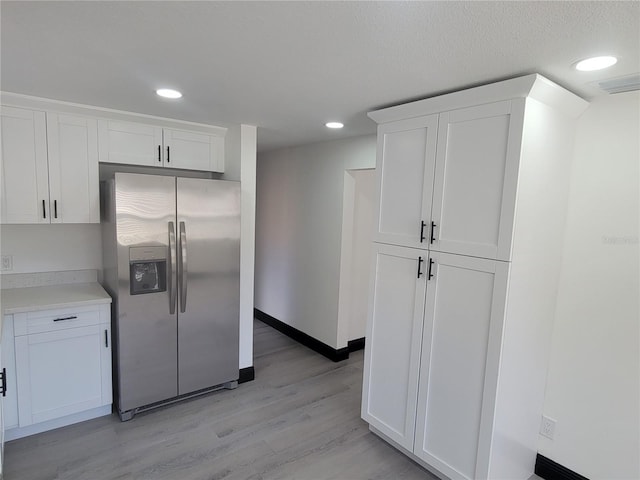 kitchen featuring stainless steel refrigerator with ice dispenser, white cabinetry, and light wood-type flooring