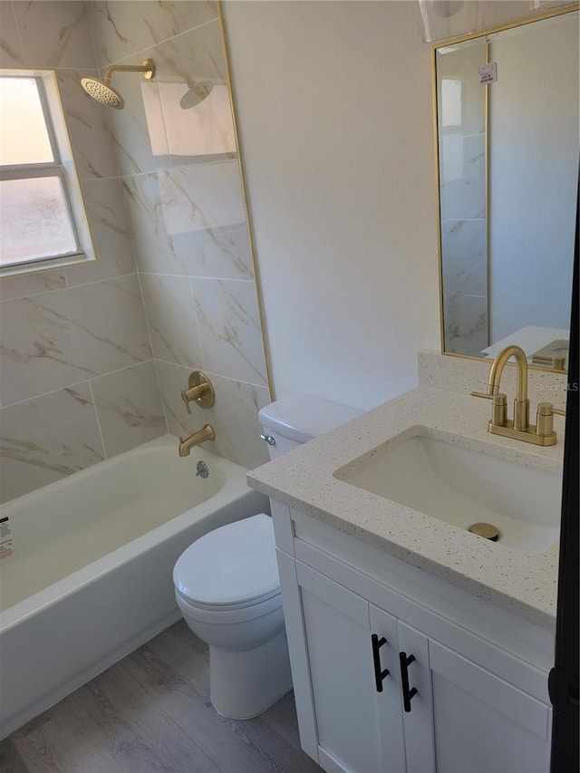 full bathroom with vanity, hardwood / wood-style flooring, tiled shower / bath, and toilet