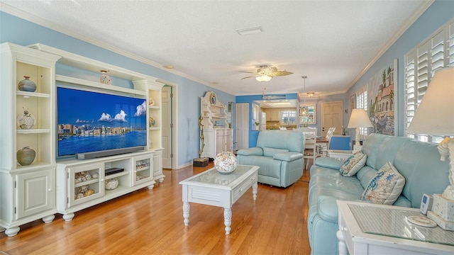 living room featuring ceiling fan, light hardwood / wood-style flooring, ornamental molding, and a textured ceiling