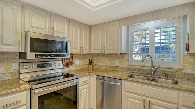 kitchen featuring sink, decorative backsplash, light stone countertops, and appliances with stainless steel finishes