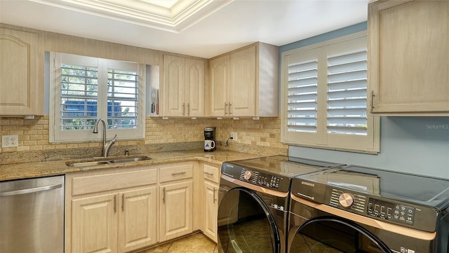 kitchen featuring light brown cabinetry, sink, stainless steel dishwasher, washer and clothes dryer, and backsplash