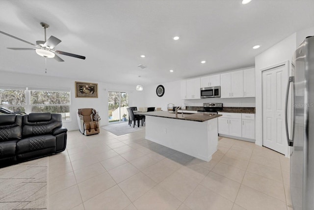 kitchen with white cabinets, an island with sink, appliances with stainless steel finishes, and light tile patterned flooring