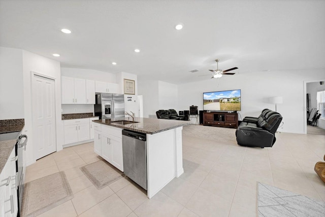 kitchen featuring appliances with stainless steel finishes, a kitchen island with sink, sink, dark stone countertops, and white cabinets