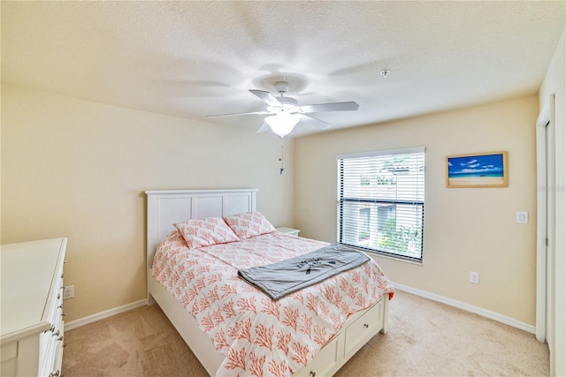 bedroom with light carpet, ceiling fan, a textured ceiling, and baseboards