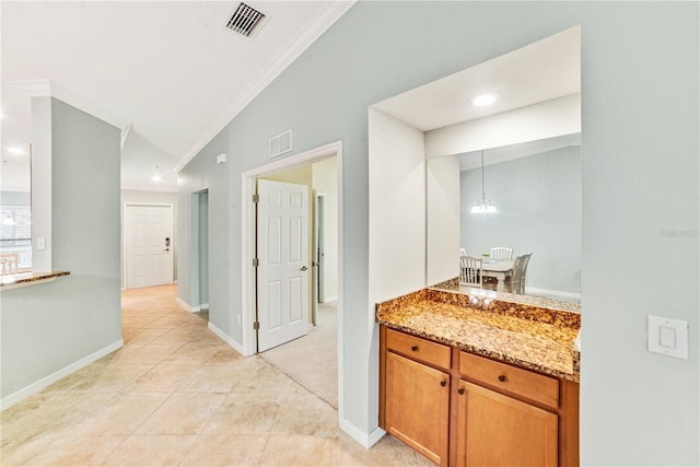 hallway with baseboards, light tile patterned floors, visible vents, and crown molding