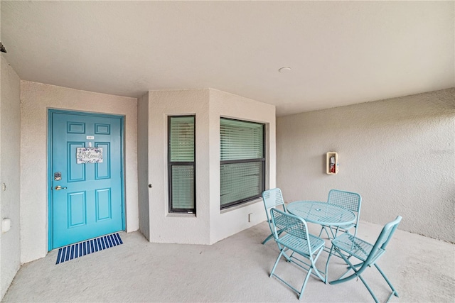 view of exterior entry featuring outdoor dining space and stucco siding