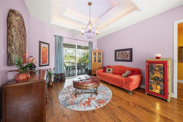 living room with a raised ceiling, hardwood / wood-style flooring, and an inviting chandelier