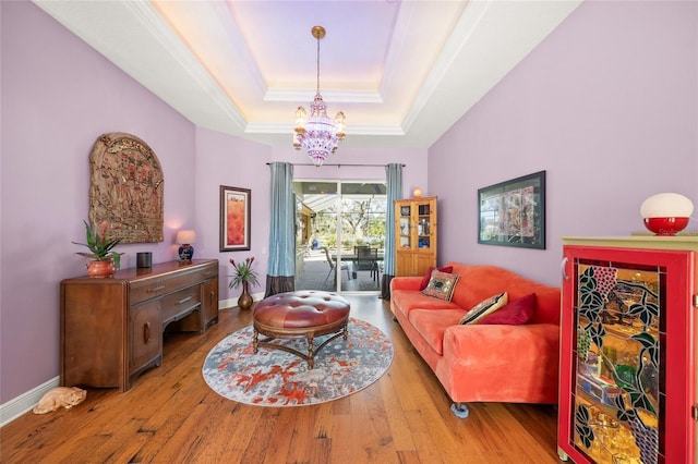 living room with a tray ceiling, light hardwood / wood-style flooring, and a notable chandelier