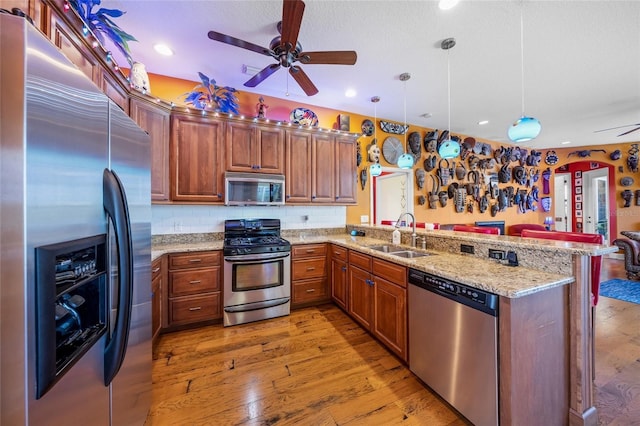 kitchen with stainless steel appliances, sink, kitchen peninsula, and decorative light fixtures