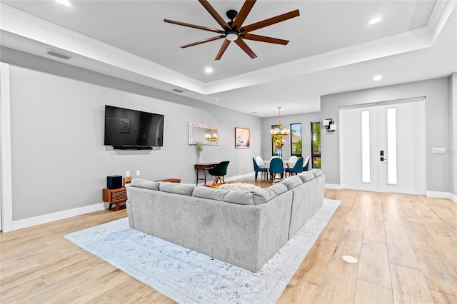 living room with a raised ceiling, french doors, and light hardwood / wood-style flooring